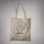 Beige tote bag with 'MYLA' logo on a light grey background
