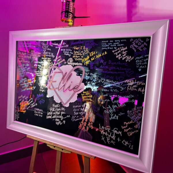 Framed bespoke mirror with signatures and a heart-shaped name 'Ellie' on a pink background