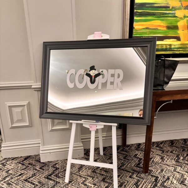 Decorative bespoke mirror with 'COOPER' branding on a stand in a room setting.