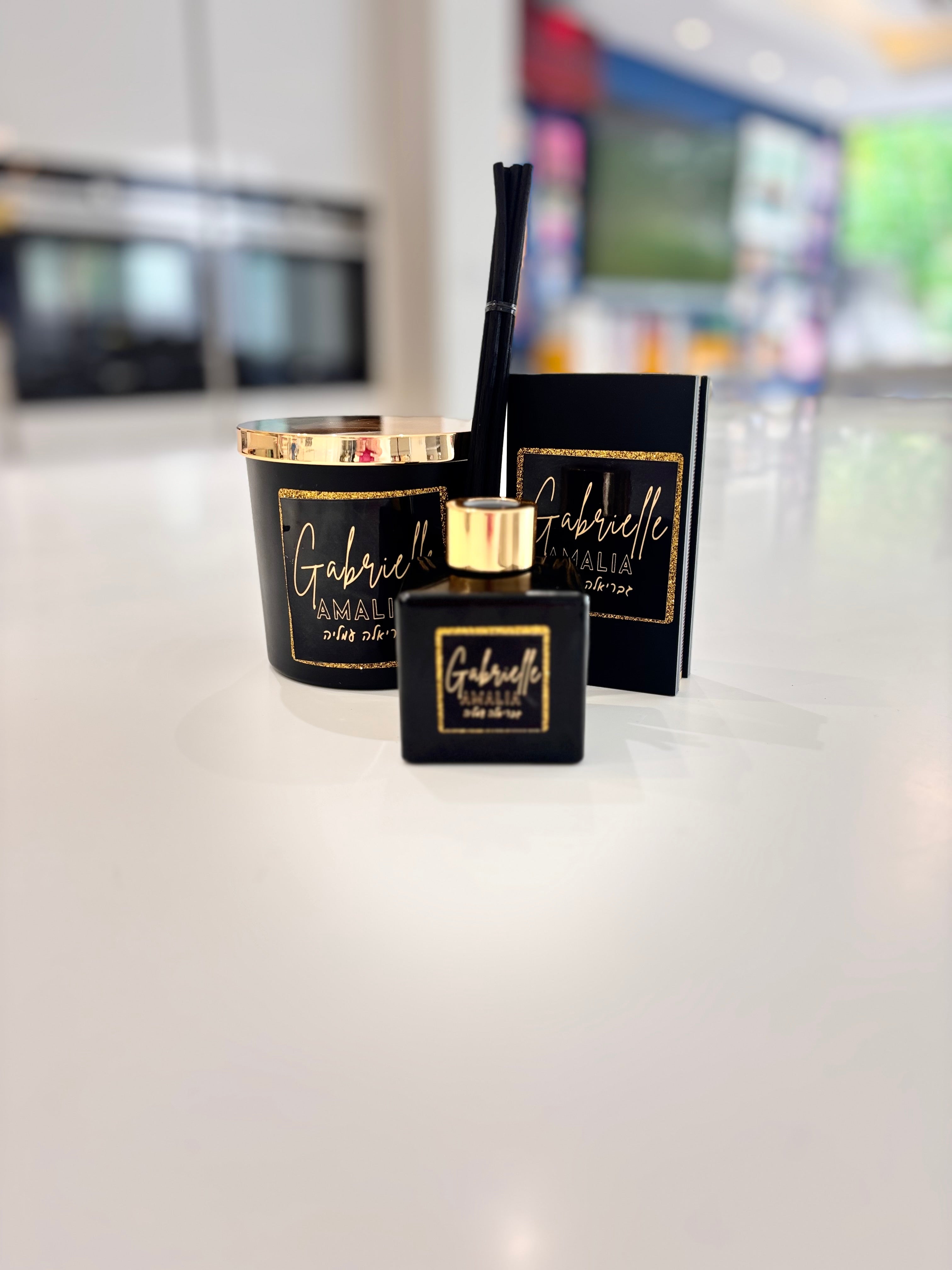 Black and gold diffuser, candle and match box set 'Gabrielle' on a white surface with a blurred background