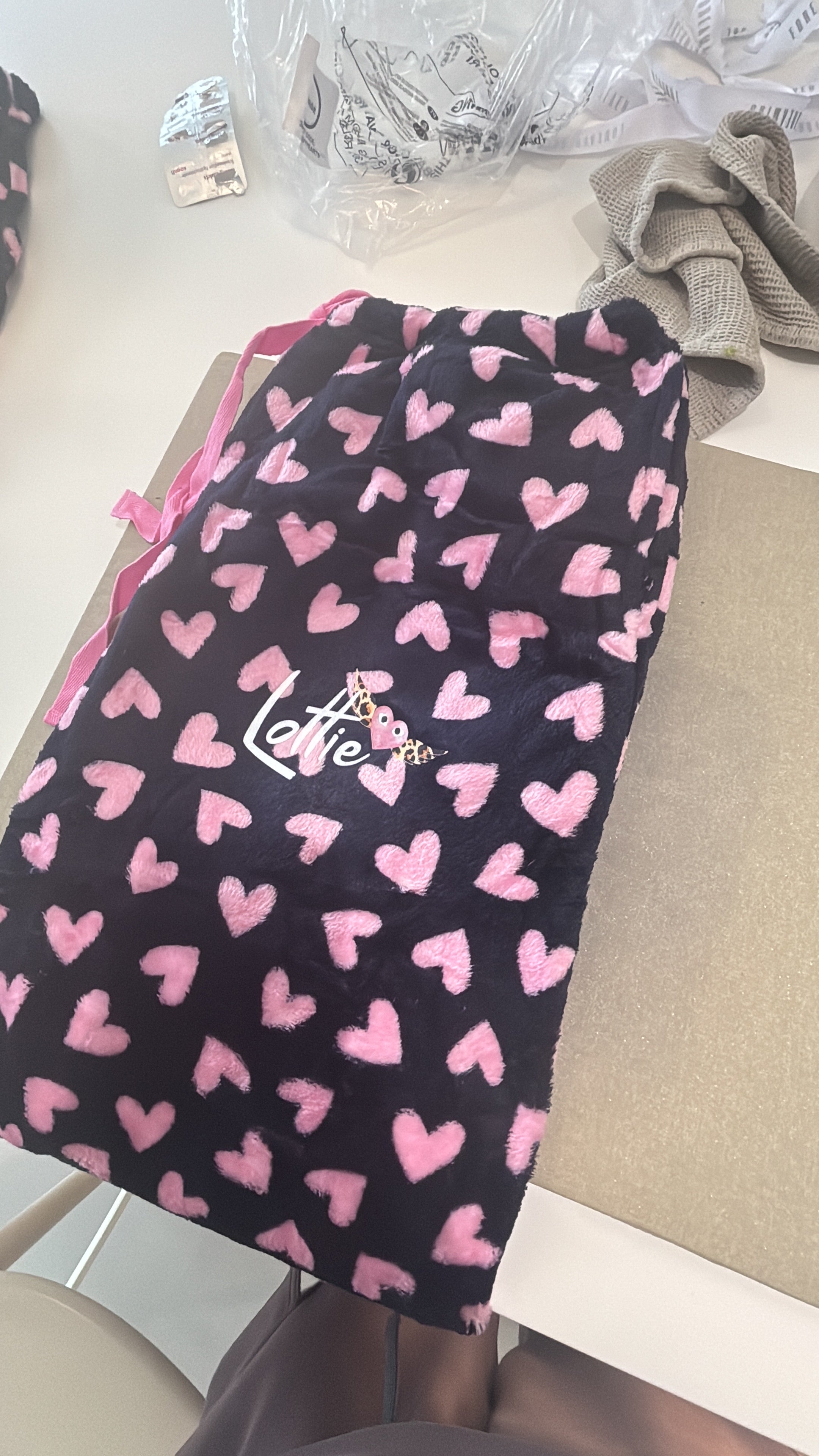 Black and pink heart patterns on pyjama trouser bottoms with 'Lottie' text