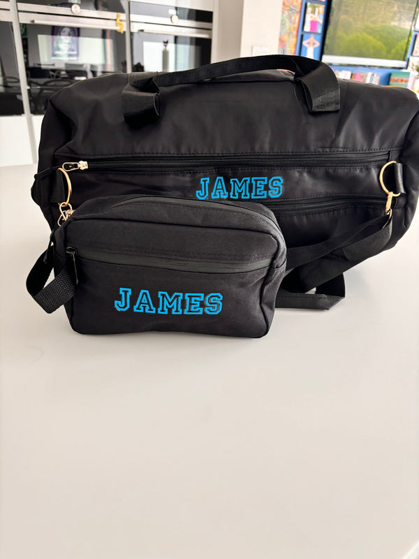 Black duffel bag and washbag and small pouch with 'JAMES' printed on them, placed on a light surface.