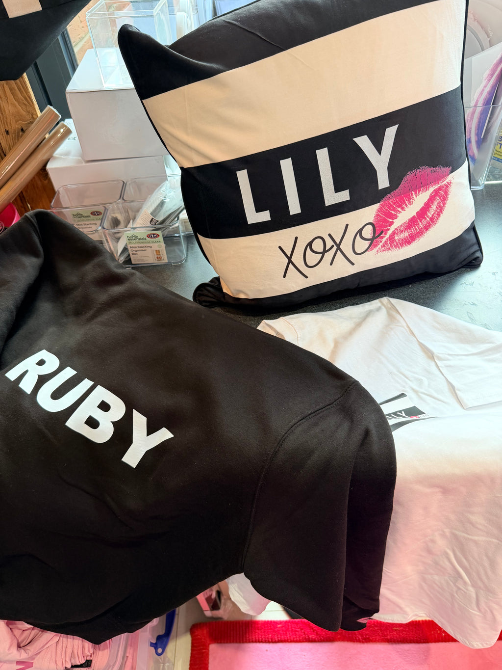Black hoodie with 'RUBY' text and a logo pillow with 'LILY' and 'XOXO' text