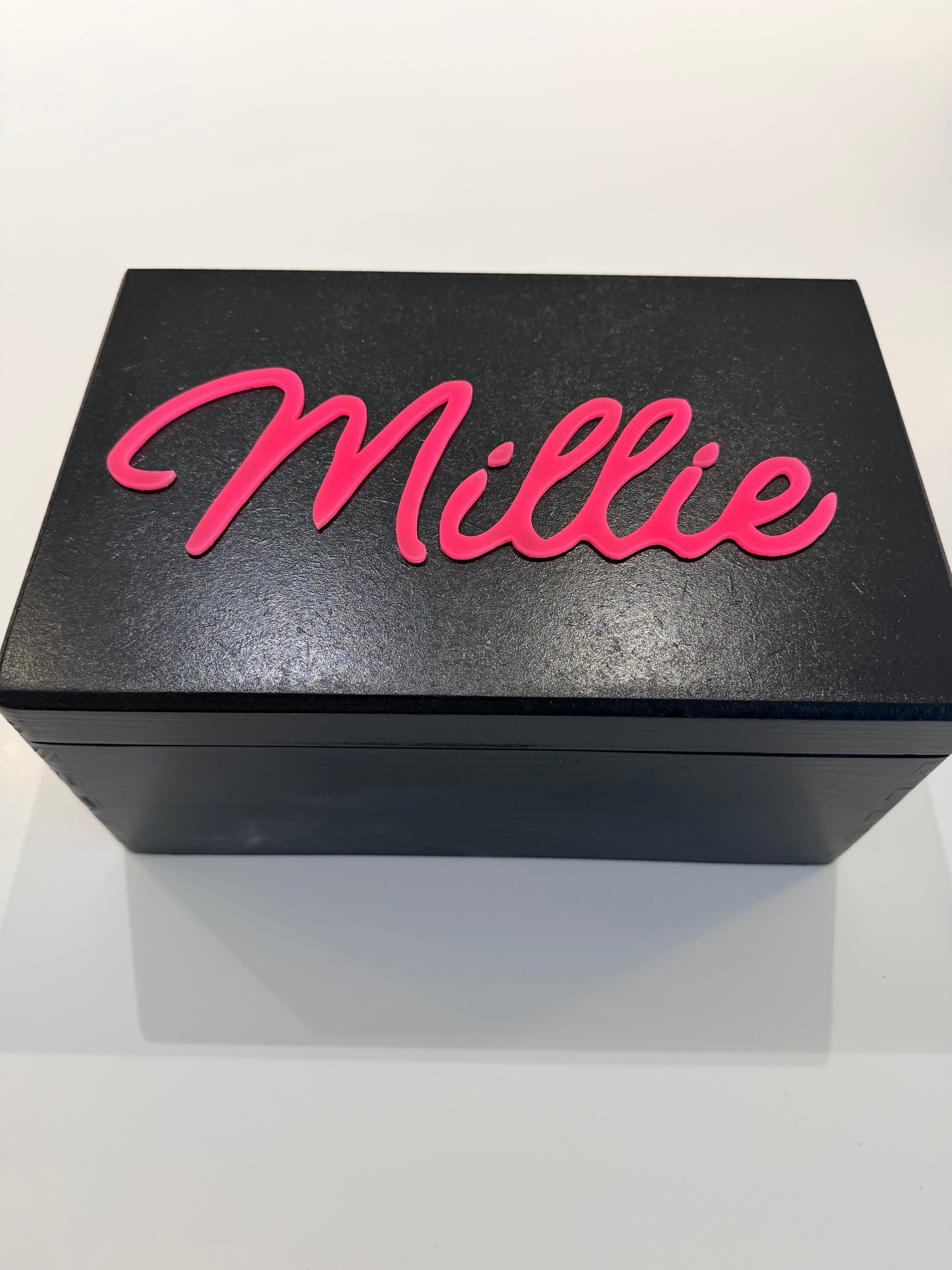 Black keepsake box with pink 'Millie' text on a white background