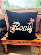 Black logo pillow with 'Romantic' text and palm tree designs on a colourful chair.