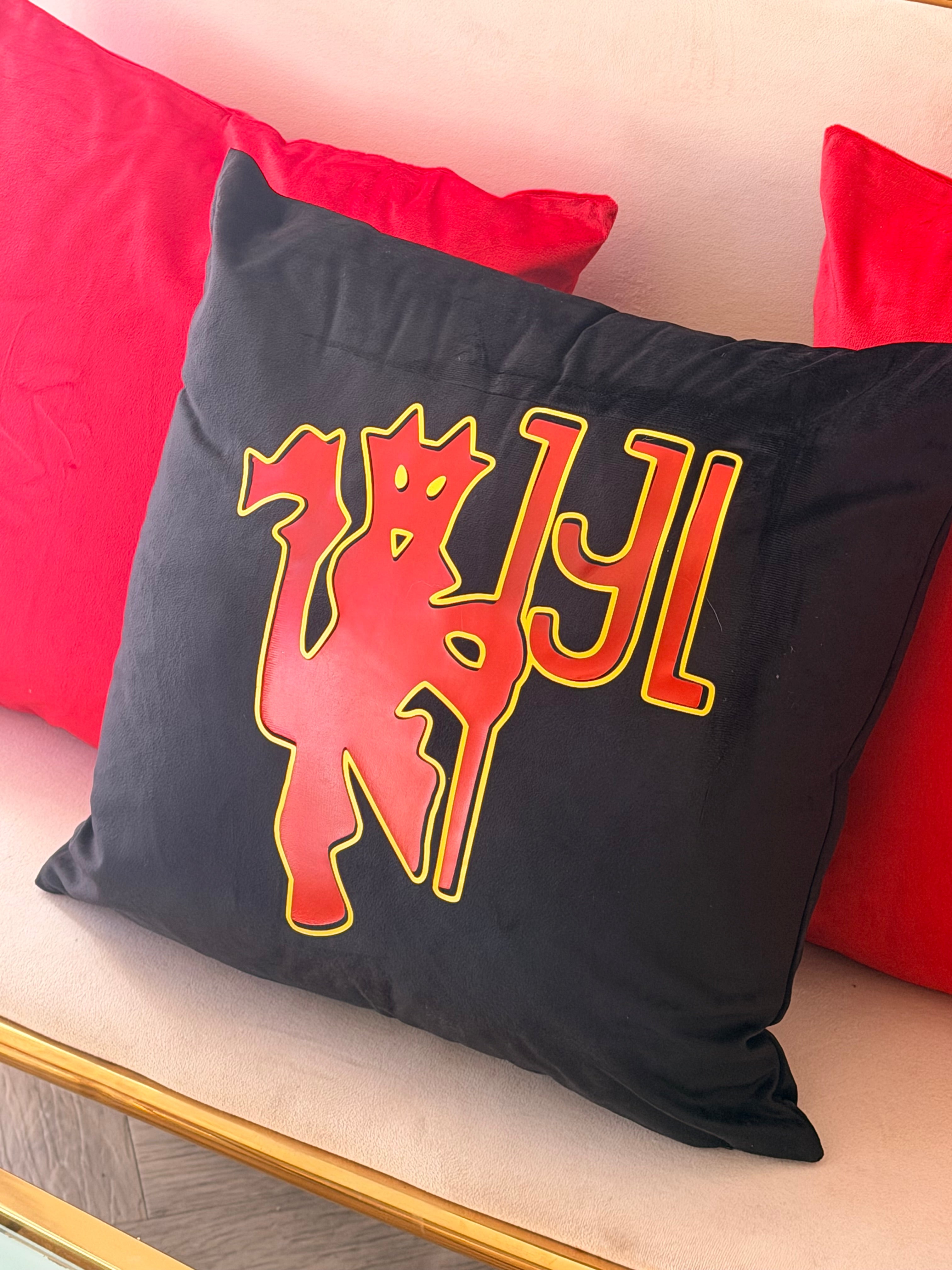 Black logo pillow with red and yellow design on a red cushion