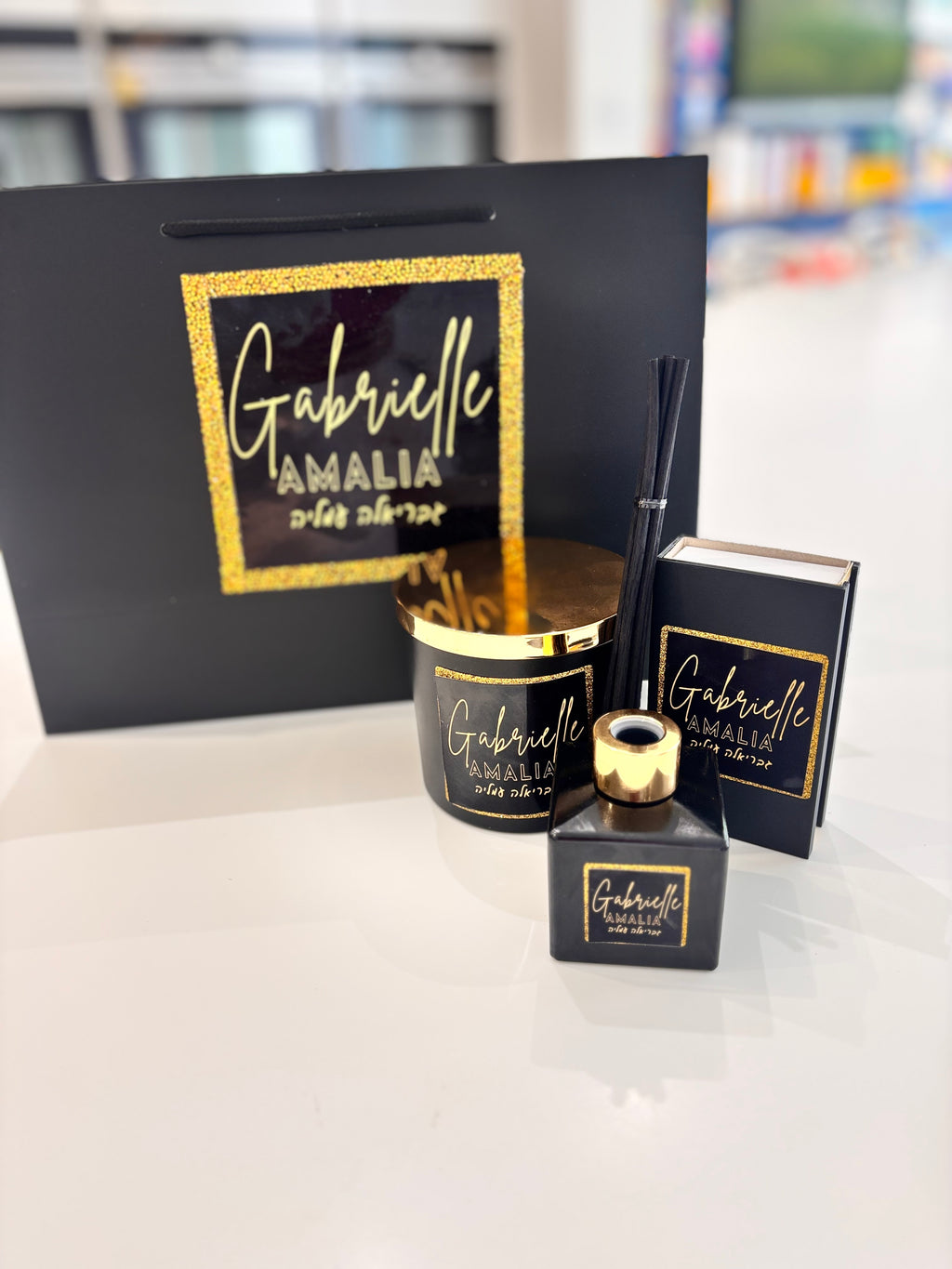 Black match box sleeve with gold text 'Gabrielle Amalia' with a candle and branded bag and diffuser.
