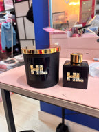 Black personalised candle and diffuser set with gold accents on a blurred store shelf background