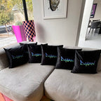 Black personalised silk pillow cases with 'Dylan' branding on a grey sofa in a living room.