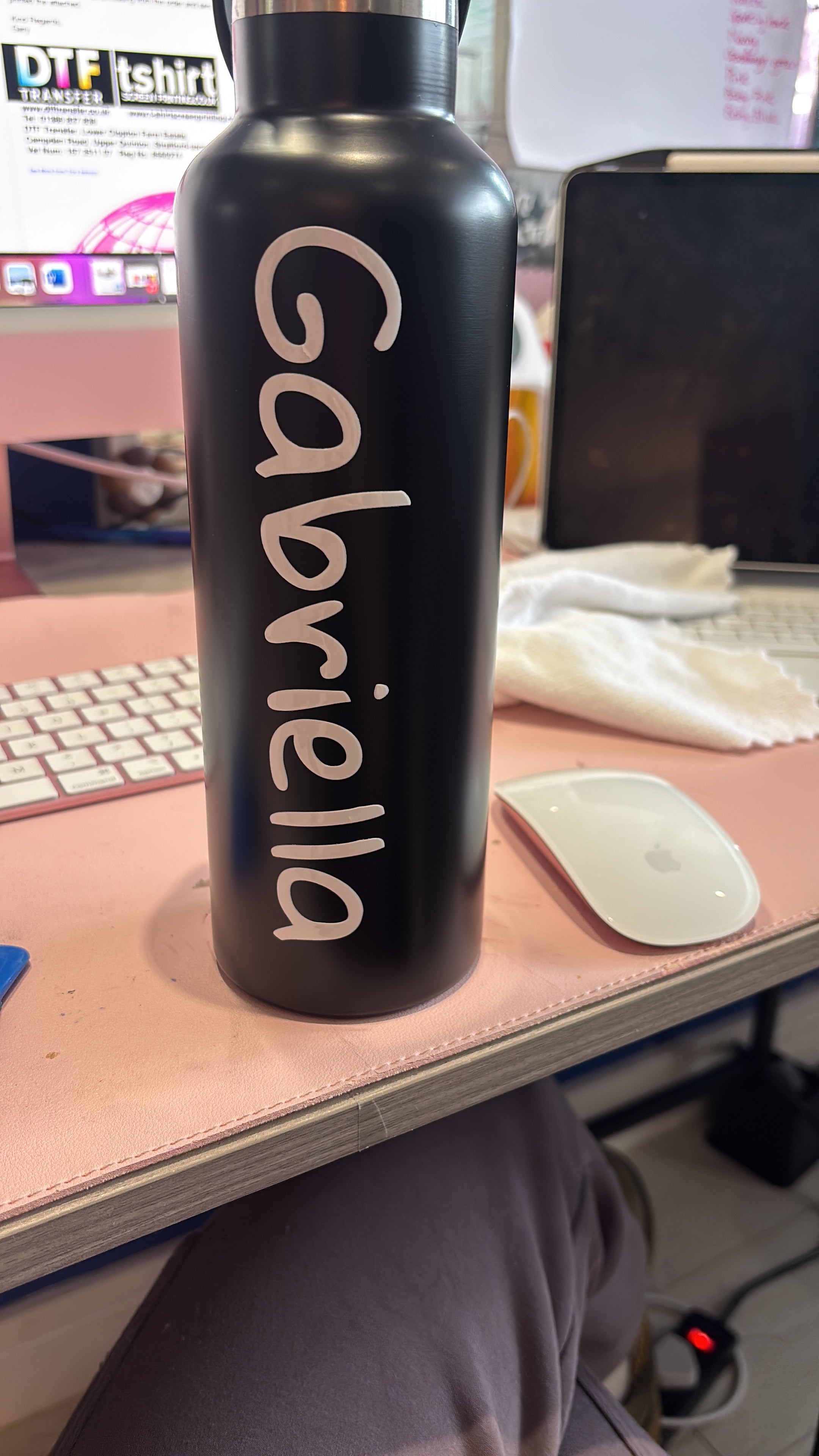 Black sports insulated water bottle with 'Gabriella' engraved on it, held by a person in a kitchen.