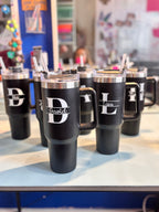 Black stanley-style cups with monograms on a table in a store setting