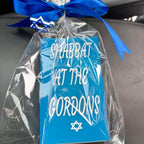 Blue match box sleeve with 'Shabbat at the Gordons' text and Star of David, wrapped in clear cellophane with a blue ribbon.