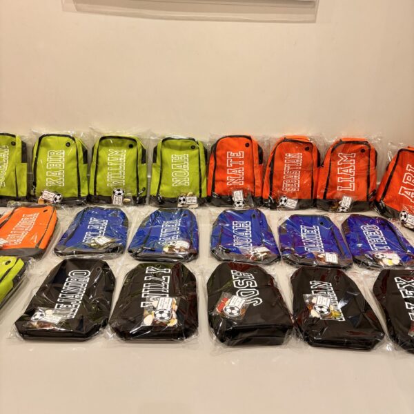 Row of colourful boot bags with visible branding on a white surface.