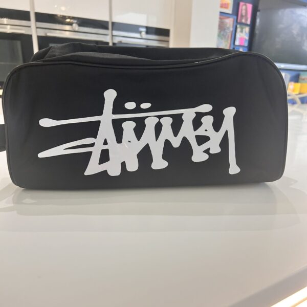 Black boot bag with white logo on a reflective surface