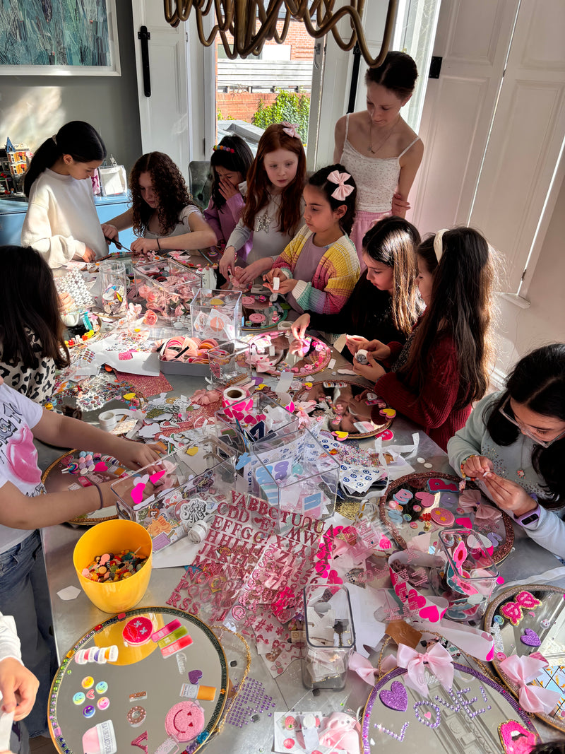 Children around a table with craft materials and decorations at a Mirrored Memories mirror party