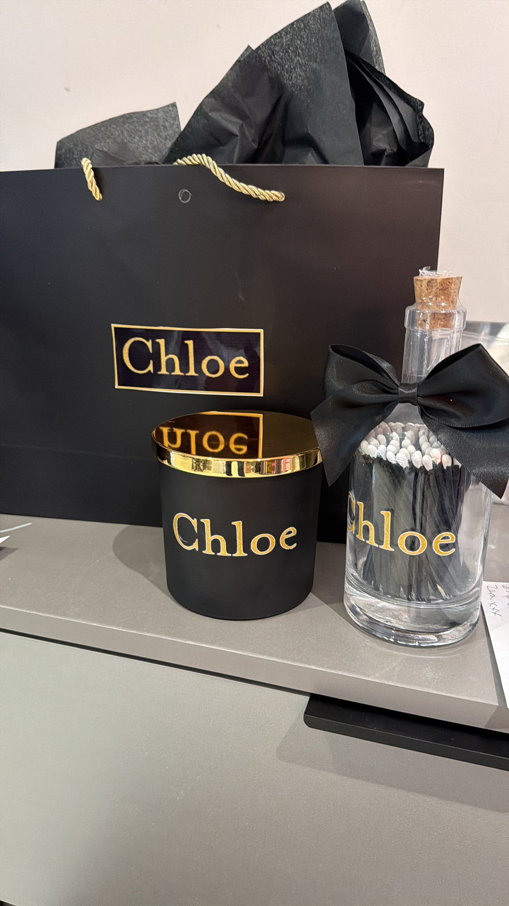 Chloe branded candle, bottle matches, and packaging on a grey surface