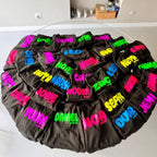 Circular arrangement of black hoodies with colourful names on a white surface.