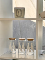 Clear glass cold cups with wooden lids on a white shelf against a grey marble background