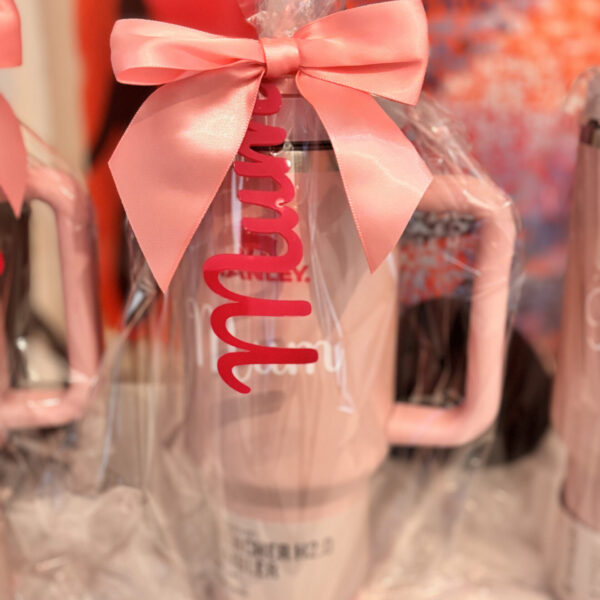Clear stanley-style cup with pink bow and 'mum' text on a blurred background.