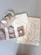Collection of personalised bags including a hat, tote bag, and laundry bag on a grey background