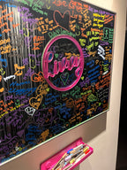 Colourful classic mirror with 'Livvy' in pink acrylic covered in names written with markers.