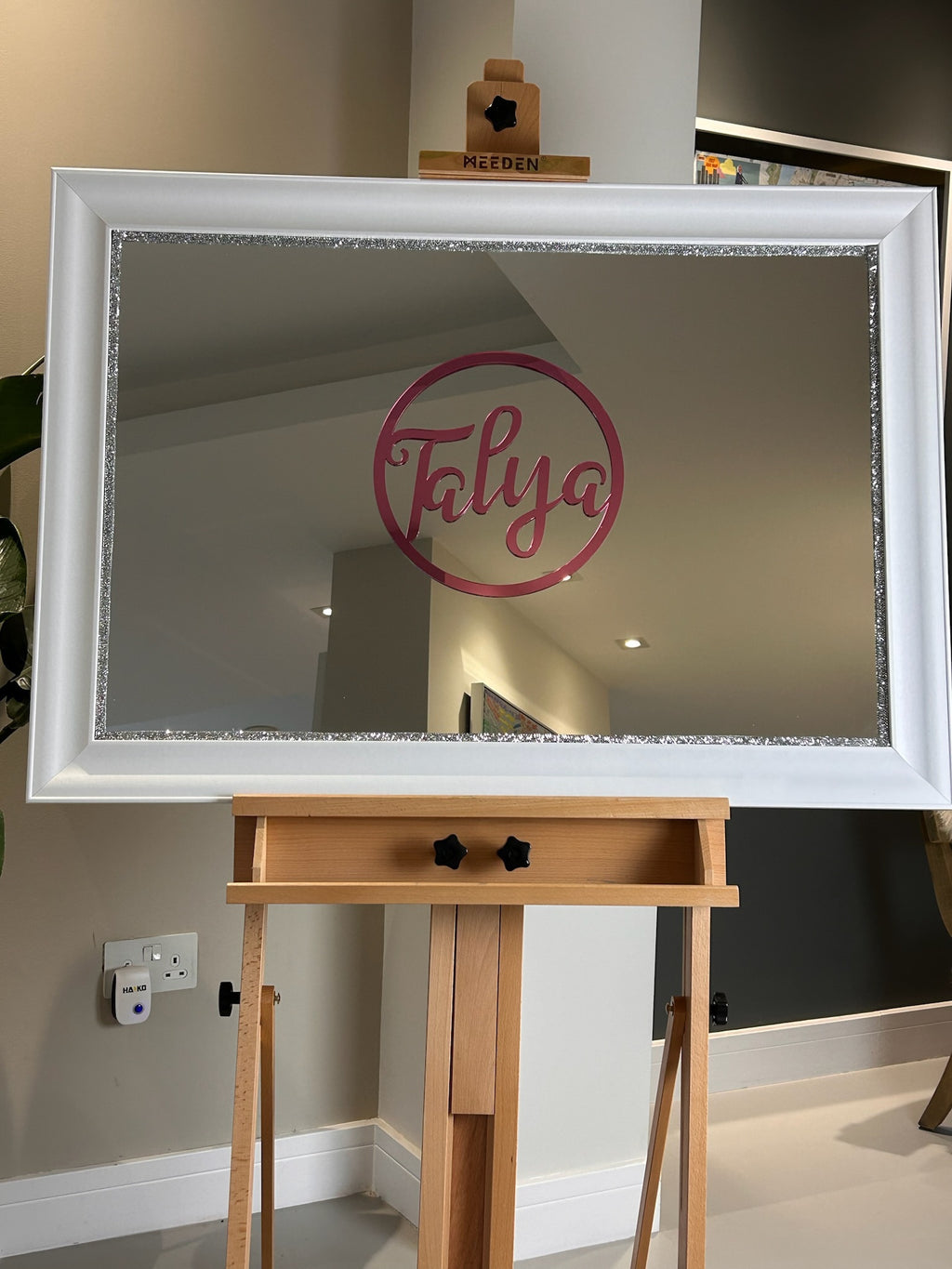 Decorative classic mirror with 'Talya' logo on a wooden stand against a neutral wall.