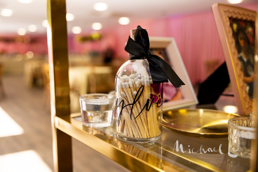 Decorative glass bottle matches with matches and a black bow on a reflective surface.