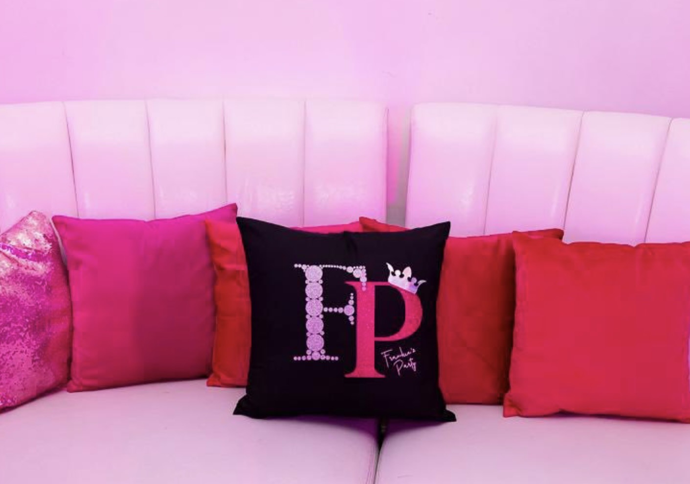 Decorative logo pillows with 'FP' logo on a pink couch