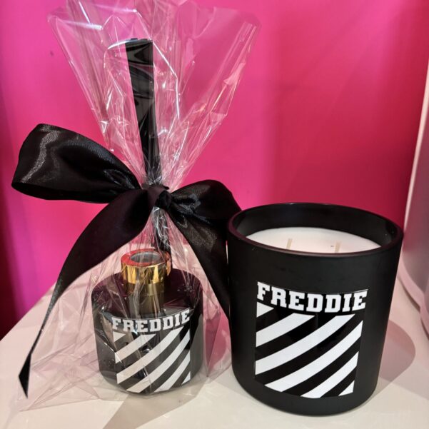 FREDDIE diffuser bottle and candle set with black ribbon against a pink background