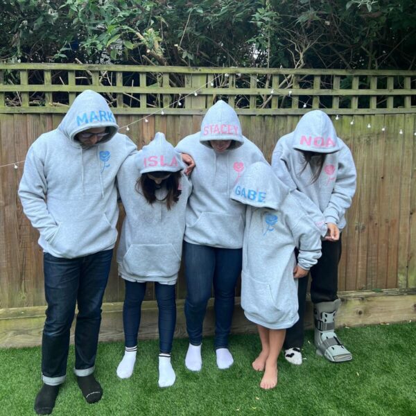 Five people wearing personalised grey hoodies in a backyard setting.