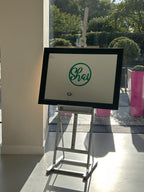 Framed classic mirror with a green logo on a stand indoors