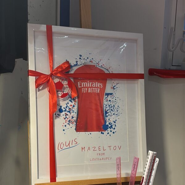 Framed football gift, red Emirates football shirt with a red ribbon, on a white background.