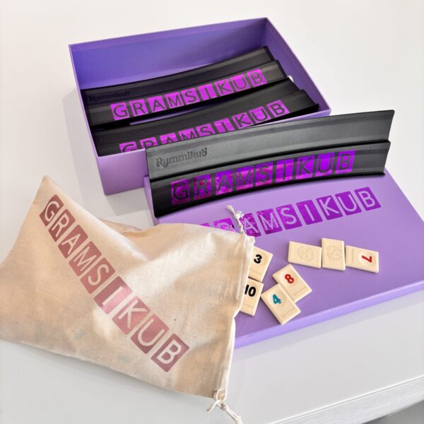 Game set with purple box, tiles, and drawstring bag on a light grey background