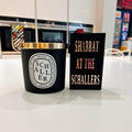 Gift set of a black Schaller candle with gold lid on a white surface, next to a black match box sleeve with 'Shabbat at the Schallers' text.