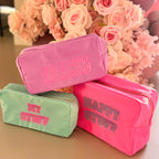 Three colourful washbags with text in front of pink flowers