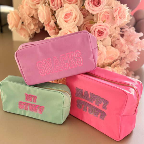 Three colourful washbags with text in front of pink flowers