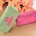 Two washbags, one mint choc chip and one raspberry ripple, with 'MY SNACKS' text in pink lettering, against a blurred floral background.