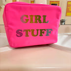 Pink washbag with 'GIRL STUFF' text in multicolour on a white surface.