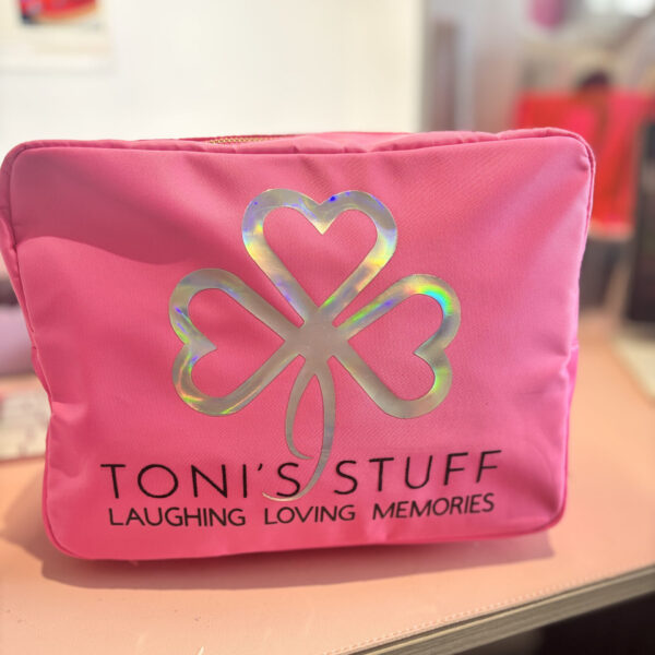 Pink washbag with a four-leaf clover design and 'TONI'S STUFF' text on a blurred background