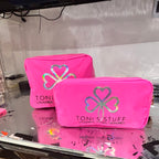 Two pink washbags with a logo and text on a reflective surface.