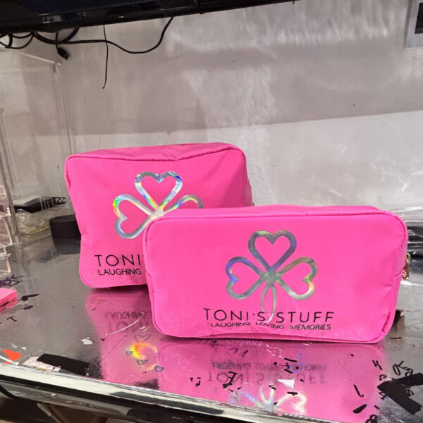 Two pink washbags with a logo and text on a reflective surface.