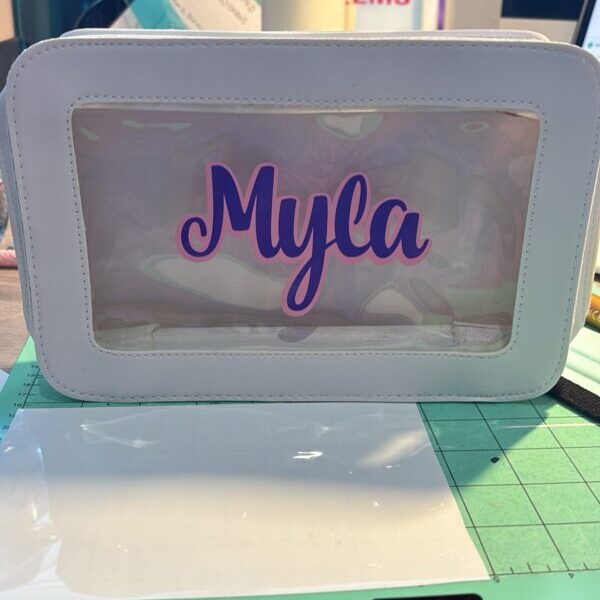 White washbag with 'Myla' printed on a clear window, on a green cutting mat.