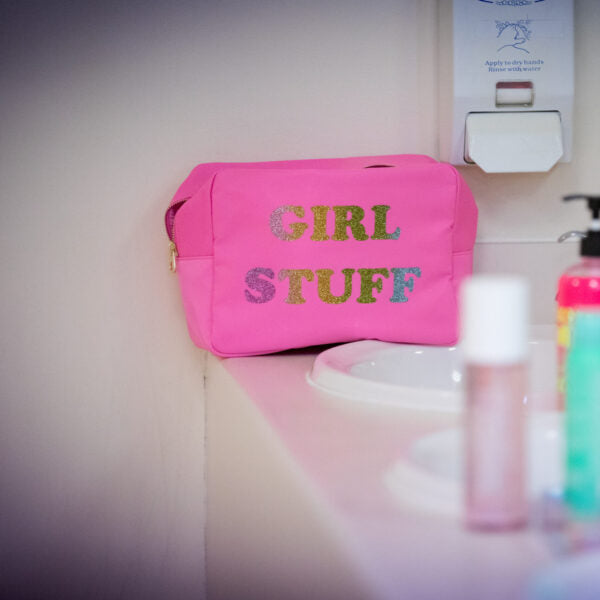 Pink washbag with 'GIRL STUFF' text on a bathroom counter.
