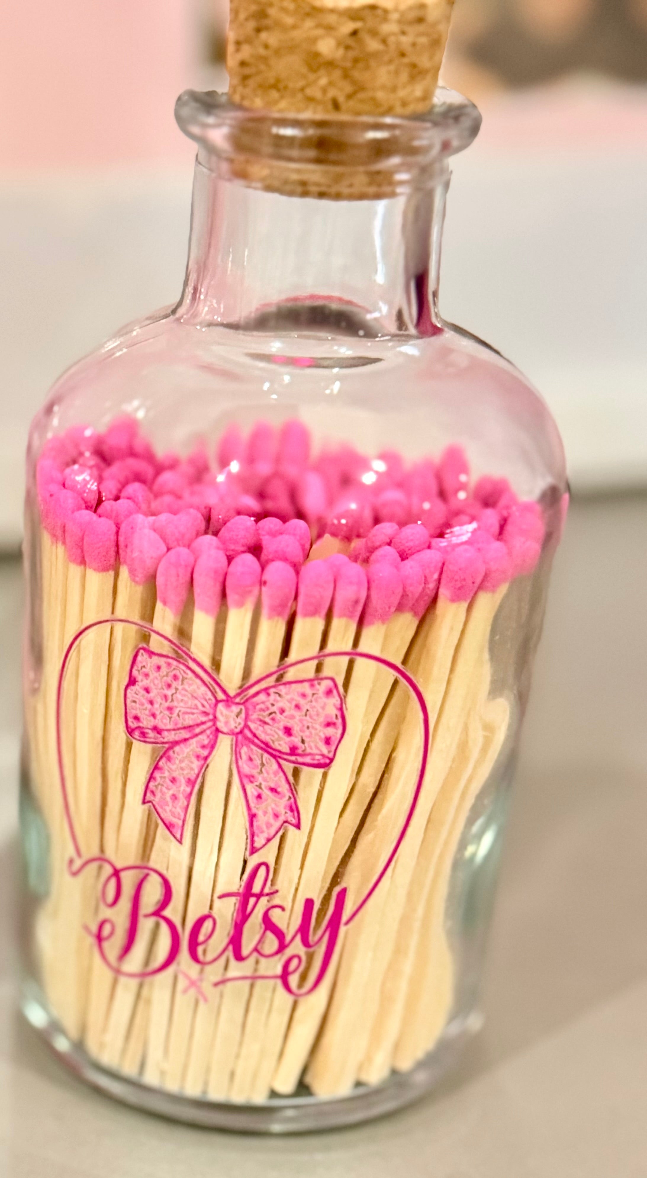 Glass bottle matches with pink matches and 'Betsy' branding on a neutral background