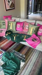 Grey sofa with decorative logo pillows featuring initials and patterns in a room.
