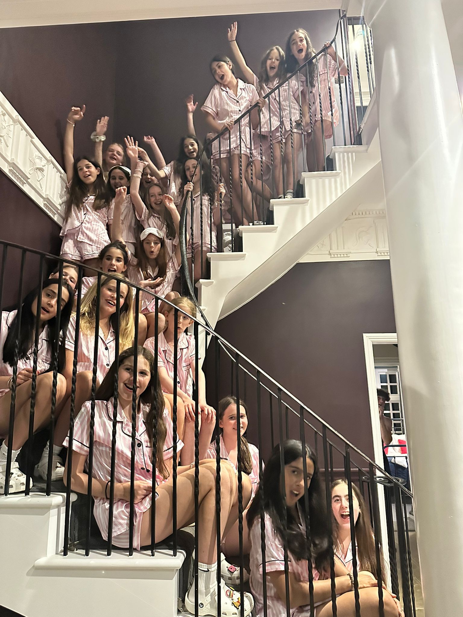 Group of people posing on a staircase with a dark wall background all wearing personalised pyjamas