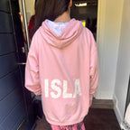 Person wearing a pink hoodie with 'ISLA' printed on the back, standing indoors.
