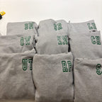 Stack of grey sweatshirts with green lettering on a white background