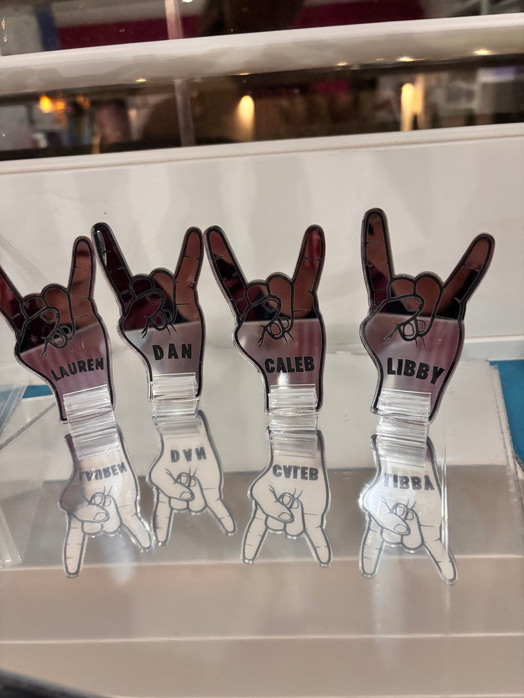 Set of personalized hand-shaped acrylic place names on a reflective surface.