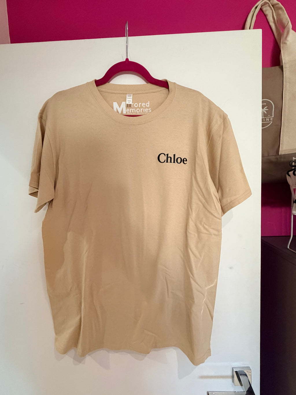 Beige event t-shirt with 'Chloe' branding on a white surface